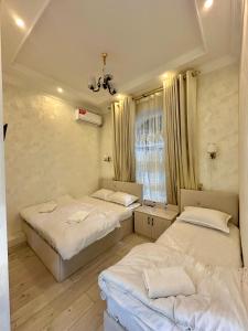 Cette chambre comprend 2 lits et une fenêtre. dans l'établissement MIRKA HOTEL LUX, à Samarcande