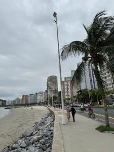 una donna e un bambino che camminano su un marciapiede vicino alla spiaggia di Linda Kitnet mobiliada a São Vicente