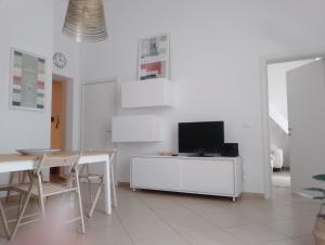Sala de estar blanca con mesa y TV en Casa Cavour, en Livorno