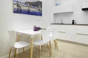 cocina con mesa blanca y sillas blancas en Zurriola Zinema by FeelFree Rentals, en San Sebastián