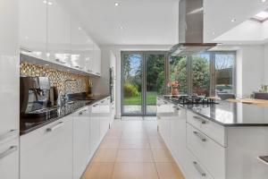 uma cozinha com armários brancos e uma grande janela em Windsor House near the Park em Hendon
