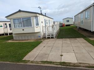 a small house with a porch next to a building at Meadow Lakes Caravan Golden palm in Chapel Saint Leonards