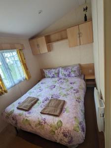 a bedroom with a bed with two towels on it at Meadow Lakes Caravan Golden palm in Chapel Saint Leonards