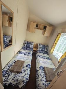 a small room with two beds and a mirror at Meadow Lakes Caravan Golden palm in Chapel Saint Leonards