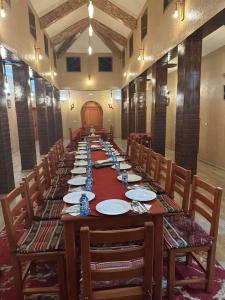 a long table in a room with chairs and plates at DAR AL QANASS IMANE in Midelt