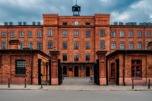 een groot bakstenen gebouw met een klokkentoren bovenop bij Your Aparts - Lofty Scheiblera in Łódź