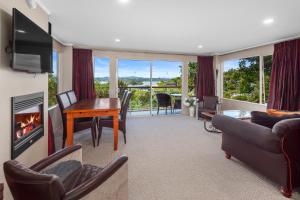 sala de estar con sofá, mesa y chimenea en Sanctuary Palms, en Paihia