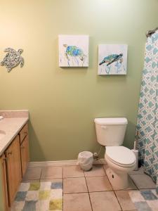a bathroom with a toilet and two paintings on the wall at Seaglass @ Orange Beach Villa in Orange Beach