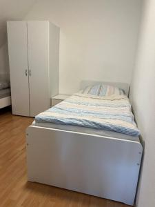 uma cama branca num quarto com um armário branco em Messezimmer nahe Flughafen direkte Verbindung Messe em Langenhagen