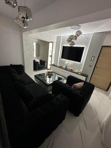 a living room with a black couch and a tv at Apartament Chloe in Tulcea