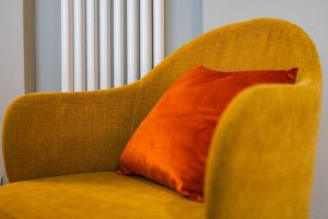 an orange pillow sitting on a yellow couch at Urban Cottage [Free Parking - Private Garden] in Bologna +15 photos