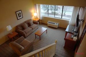 ein Wohnzimmer mit einem Sofa, Stühlen und einem Fenster in der Unterkunft Ramada by Wyndham Kelowna Hotel & Conference Center in Kelowna