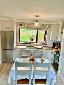 een keuken met een tafel en 2 stoelen en een koelkast bij The Cosy Farm Cottage, Donegal in Inver