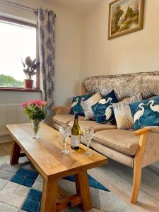 een woonkamer met een bank en een tafel met wijnglazen bij The Cosy Farm Cottage, Donegal in Inver