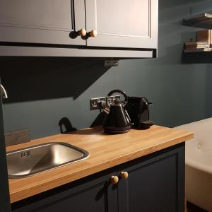 a kitchen sink with a tea kettle on a counter at Recently extended garden apartment near JR and Oxford in Oxford