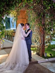 een bruid en bruidegom die kussen onder een boog bij Eventos Villa Garden in Aracaju