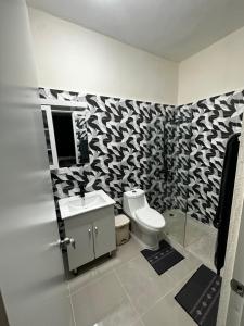 baño con aseo y pared estampada en blanco y negro en Hotel Mi Dulce Amanecer PyR, en Nagua