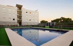 a large swimming pool in front of a building at ApartHome® in Bormujos