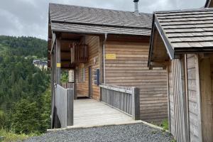 a wooden cabin with a wooden walkway in front at Chalet au pied des pistes, le lioran, terrasse, 2 chambres, 4 lits in Laveissière