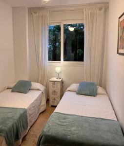 2 camas en una habitación con ventana en Jerez, zona norte, Cadiz, España en Jerez de la Frontera