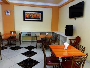 een restaurant met tafels en stoelen en een flatscreen-tv bij Hotel Challaca in Ica