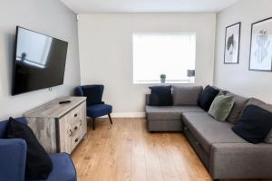 a living room with a couch and a flat screen tv at Comfortable 3 Bed House with Parking, WiFi & Patio by Ark SA in Handsworth