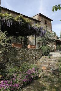 un edificio de piedra con glicinas púrpuras creciendo en él en Casa Corzanello, en San Casciano in Val di Pesa