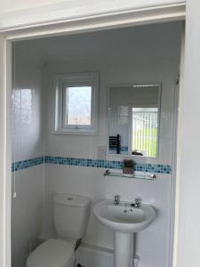 a white bathroom with a toilet and a sink at Chalet in Stalham in Stalham