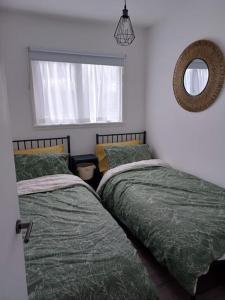 a bedroom with two beds and a mirror and a window at Chalet in Stalham in Stalham