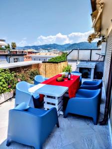 -Penthouse con Terrazza Panoramica -Free Parking- في كارارا: فناء مع طاولة حمراء وكراسي زرقاء