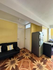 Disha's Home Casa Hospedaje في اياكوتشو: غرفة معيشة مع أريكة سوداء وثلاجة