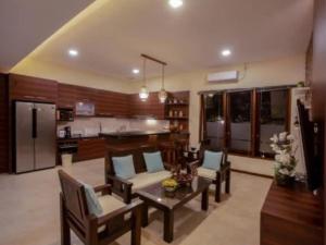 sala de estar con sillas, mesa y cocina en Dawn Golf Villa, en Tanjung