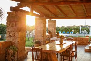 a patio with a wooden table and chairs at Ugento Country Cottage - Villa con Piscina in Ugento