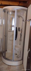 La salle de bains est pourvue d'une douche avec une porte en verre. dans l'établissement Holiday Apartment Agapi, à Kamilárion
