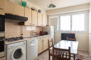 a kitchen with a washing machine and a table with chairs at Lovely 66 m 2 steps from the city center in Boulogne-Billancourt