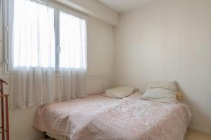 a white bedroom with a bed and a window at Lovely 66 m 2 steps from the city center in Boulogne-Billancourt
