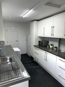 una cocina con armarios blancos y fregadero en Entire 6 bedroom house in Oldham en Moston