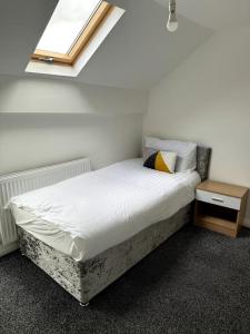 a bed in a room with a window at Entire 6 bedroom house in Oldham in Moston