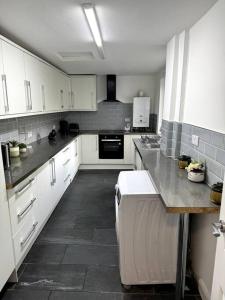 uma cozinha com armários brancos e piso em azulejo em Entire 6 bedroom house in Oldham em Moston
