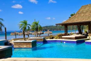 uma piscina num resort com palmeiras e uma praia em Steps From Ocean Couple's Getaway Private Villa em Playa Venao