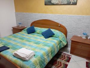 a bedroom with a bed with blue pillows at B&B I Tre Ulivi in Morro dʼOro