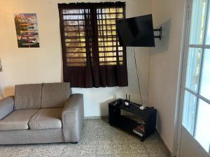 a living room with a couch and a flat screen tv at Coqui del corazón Guest House in Hatillo