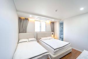 2 camas en una habitación con paredes blancas en Boutique hotel with outdoor barbeque #pet friendly, en Incheon