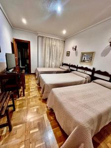 a room with four beds and a desk with a computer at Hotel Residencia Castellano I in Salamanca