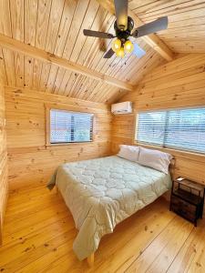 ein Bett in einem Holzzimmer mit Deckenventilator in der Unterkunft 1 Bedroom Log Cabin on Lake James-Private Resort Amenities in Marion