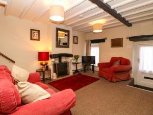 sala de estar con muebles de color rojo y chimenea en Shippon Cottage en Castleton
