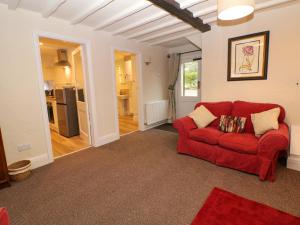 a living room with a red couch and a kitchen at Shippon Cottage in Castleton