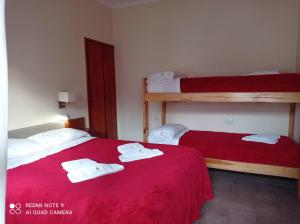 two beds in a room with red sheets and white towels at Hostería Robert in Villa Gesell