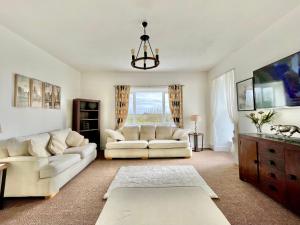 a living room with two white couches and a window at Clydfan in Holyhead