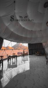 a tent with tables and chairs and a large window at Sama Wadi Rum in Wadi Rum